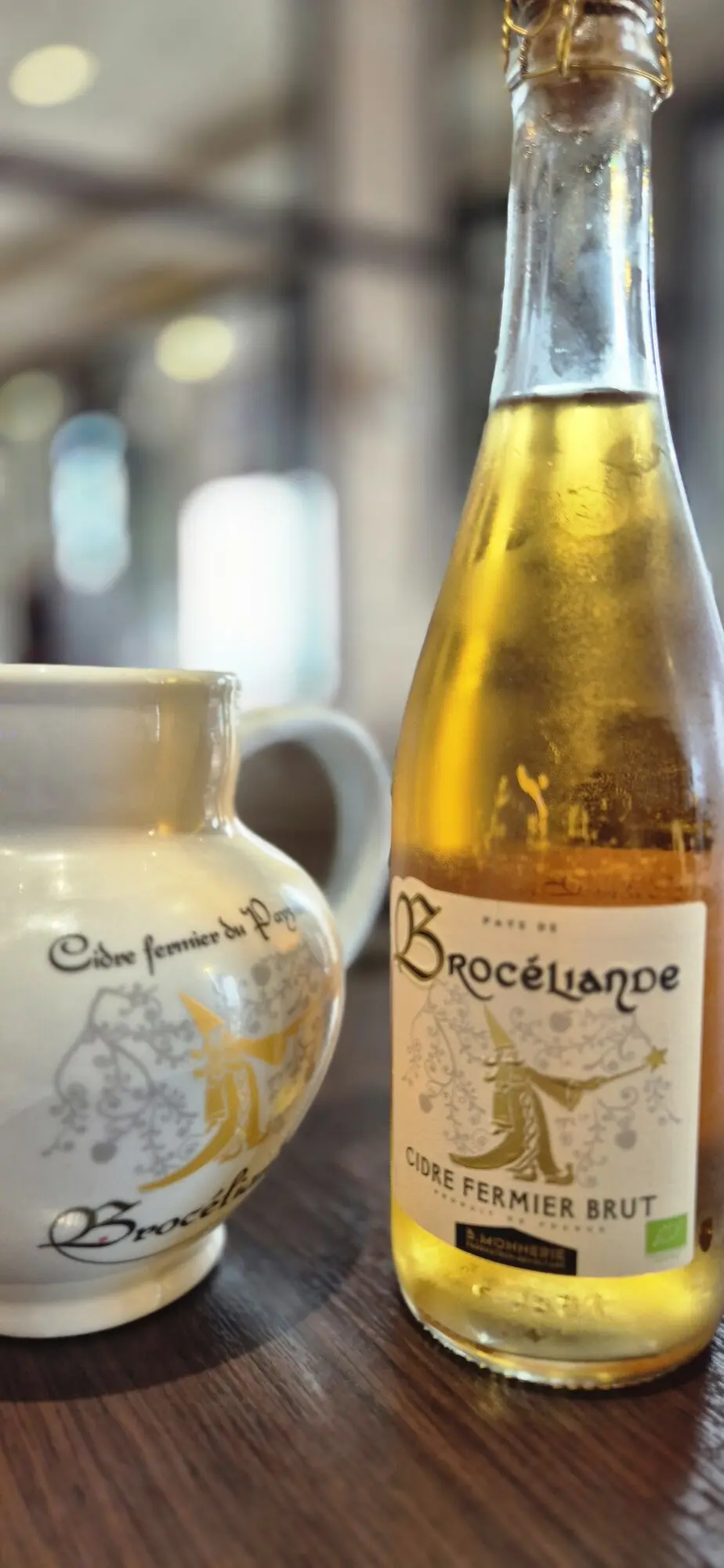Bouteille de cidre fermier Brocéliande et pichet en grès sur une table