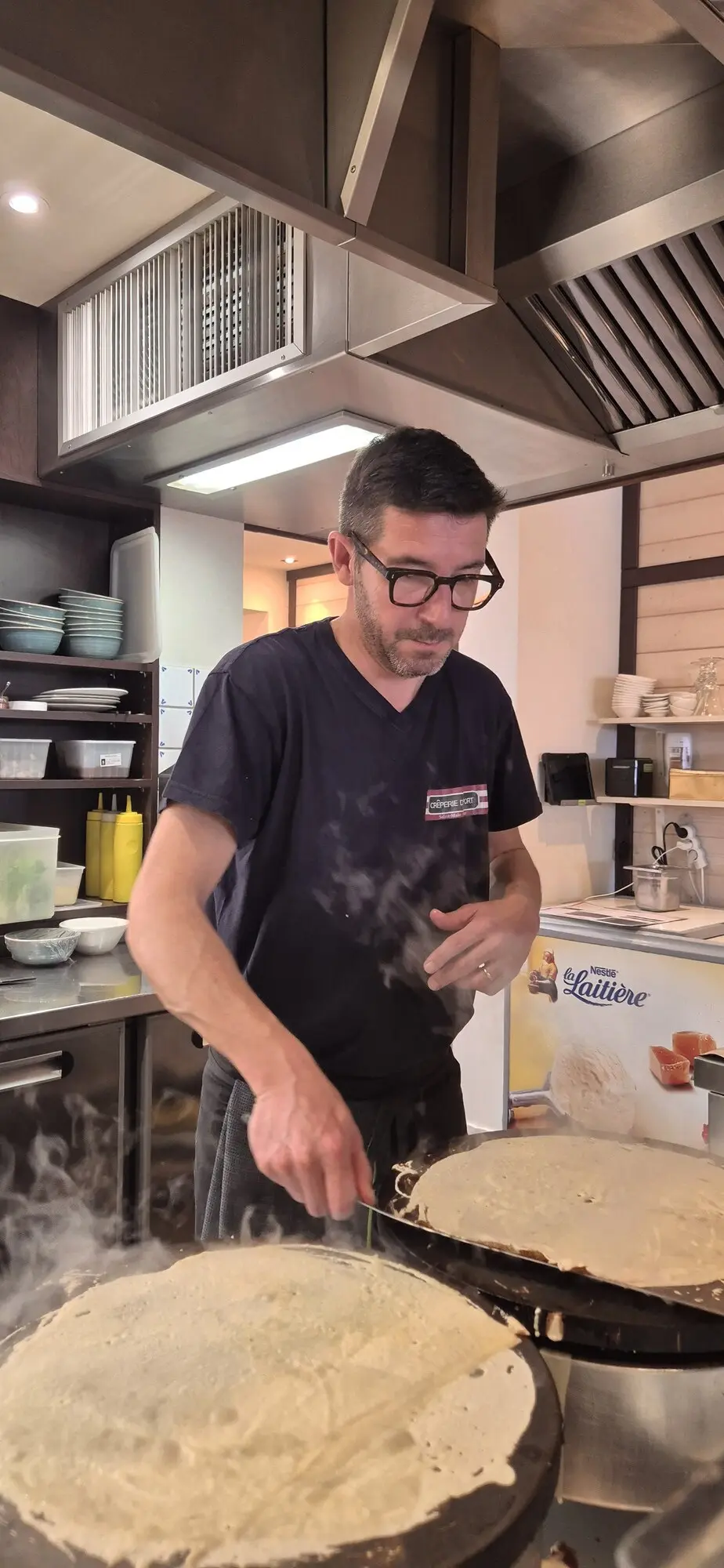 Le crêpier étale la pâte sur le billig, vapeur de cuisson