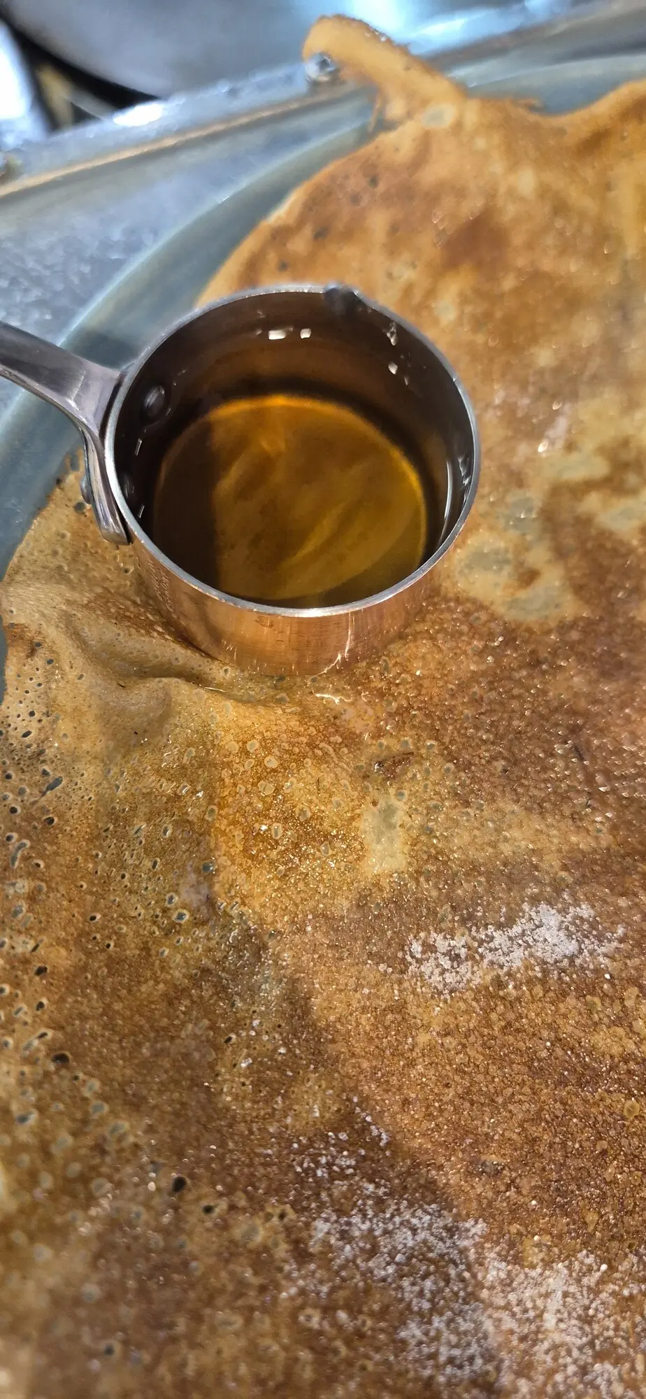 Gros plan sur une galette de blé noir et une louche de caramel au beurre salé